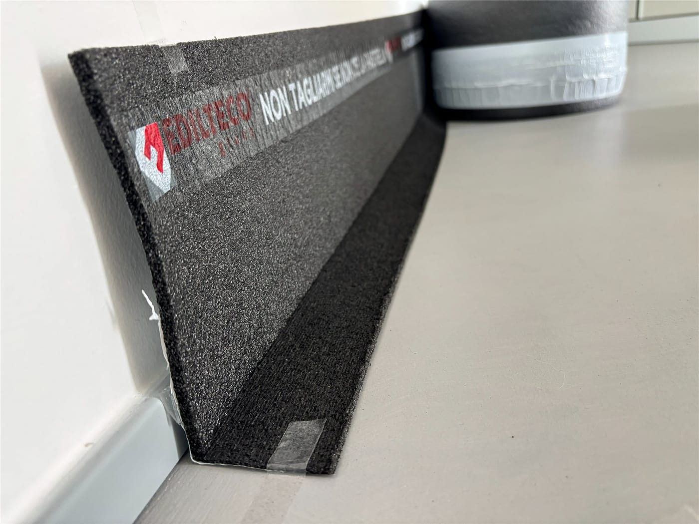 “L”-shaped perimeter strip separating screed and wall